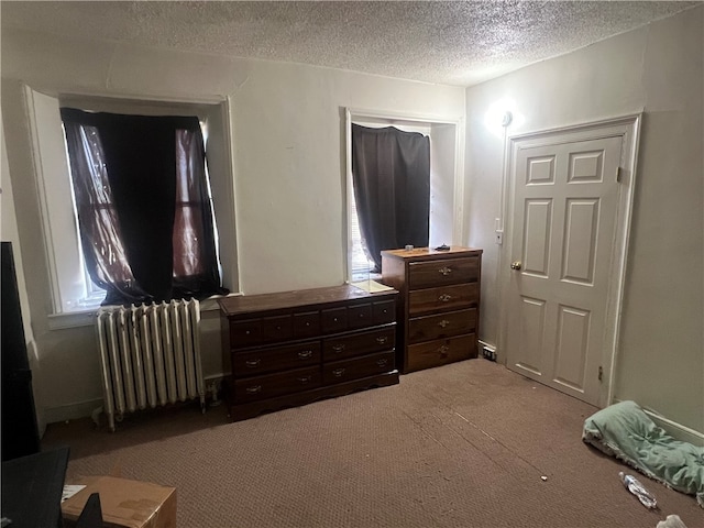 carpeted bedroom featuring a textured ceiling and radiator heating unit