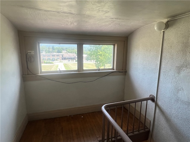 staircase featuring hardwood / wood-style floors, a textured ceiling, a wealth of natural light, and lofted ceiling