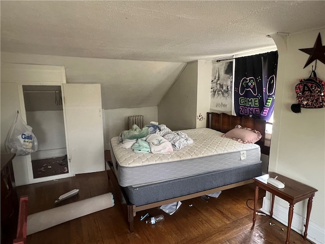 bedroom with radiator heating unit, a textured ceiling, lofted ceiling, and hardwood / wood-style flooring