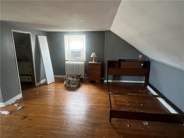 additional living space featuring radiator heating unit, wood-type flooring, lofted ceiling, and cooling unit