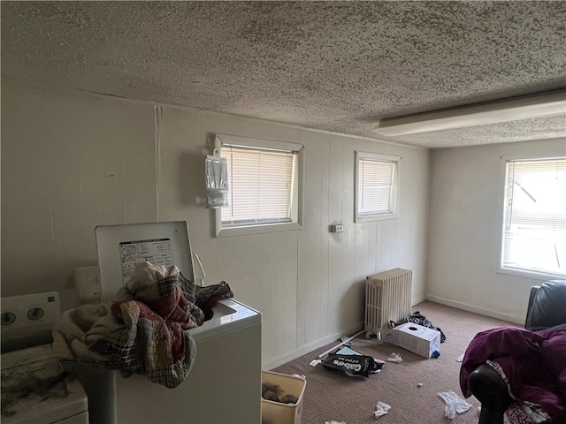 misc room with washer / dryer, a textured ceiling, radiator, and light carpet