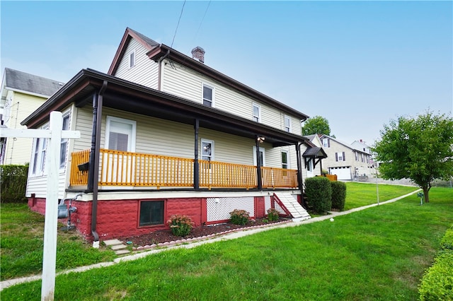 back of house with covered porch, a yard, and a chimney