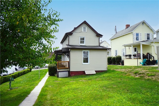 back of house featuring a lawn and covered porch