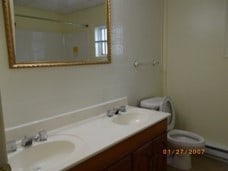 bathroom with double vanity, a baseboard radiator, and toilet