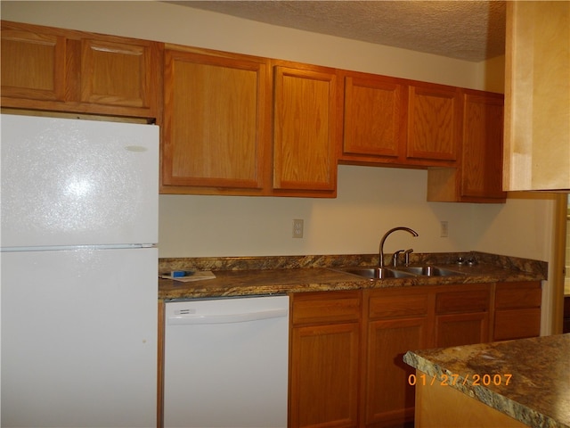 kitchen featuring a textured ceiling, white appliances, sink, and dark stone countertops