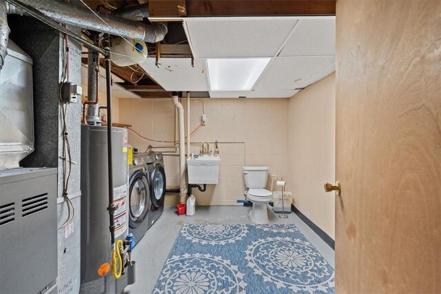 laundry area featuring gas water heater, washing machine and clothes dryer, and sink