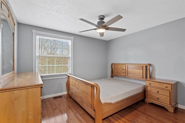 bedroom with ceiling fan, a textured ceiling, and hardwood / wood-style floors