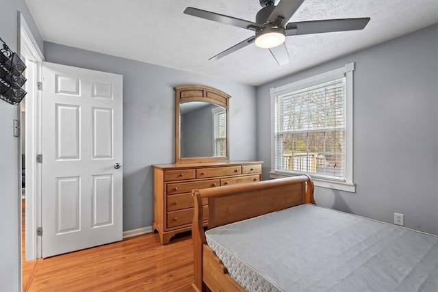 bedroom featuring ceiling fan, light wood-type flooring, and a textured ceiling