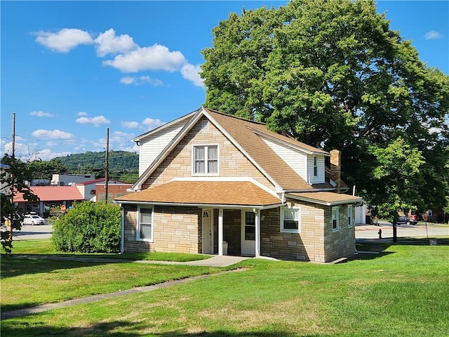 view of front of house featuring roof with shingles, a front lawn, and a chimney