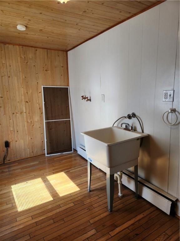 unfurnished office featuring a baseboard radiator, wood walls, hardwood / wood-style floors, and wooden ceiling