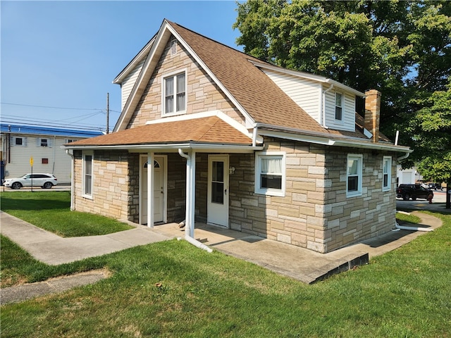 view of front of property featuring a shingled roof, stone siding, a chimney, a porch, and a front lawn