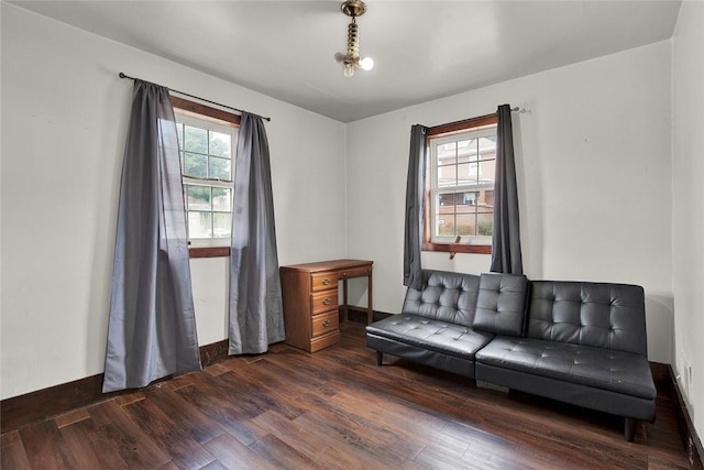 living area with dark wood-style flooring, plenty of natural light, and baseboards