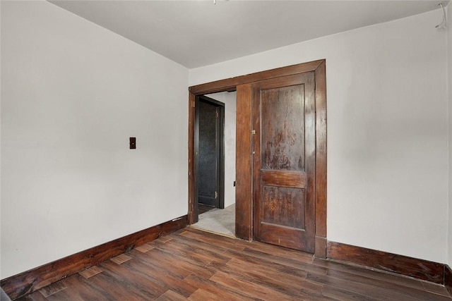 empty room featuring dark wood-style floors and baseboards