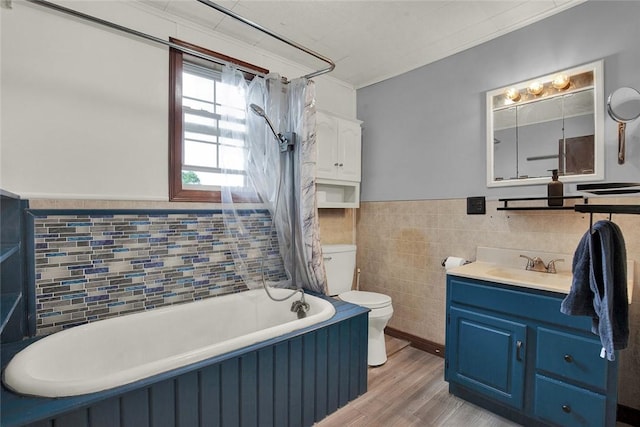 bathroom with toilet, wood finished floors, vanity, wainscoting, and shower / bath combo