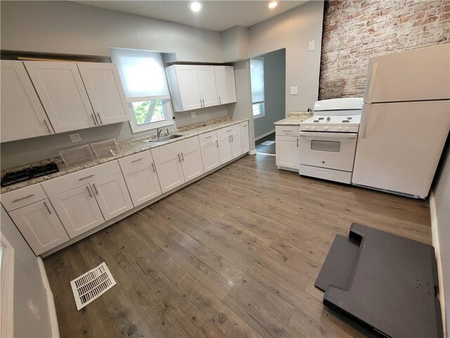 kitchen featuring white cabinetry, light stone countertops, light wood-type flooring, white appliances, and sink