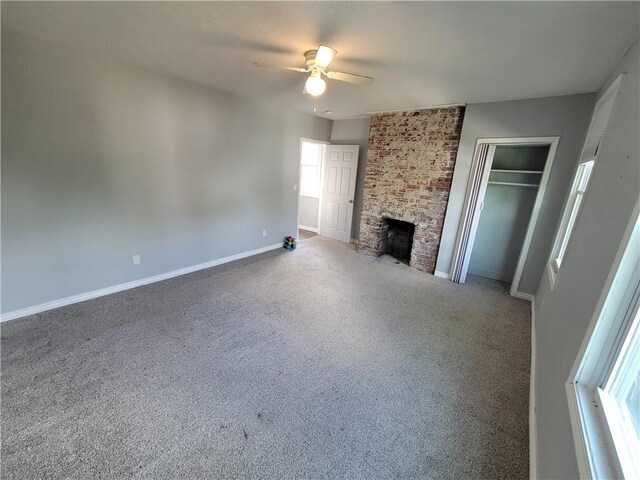 unfurnished living room featuring ceiling fan and a brick fireplace