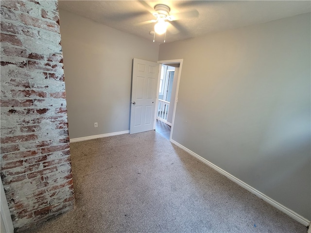 carpeted empty room featuring brick wall and ceiling fan