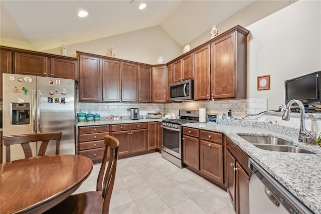 kitchen with light tile patterned floors, appliances with stainless steel finishes, sink, backsplash, and light stone counters