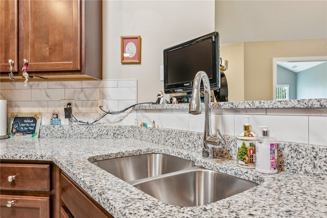 kitchen featuring decorative backsplash, sink, and light stone countertops