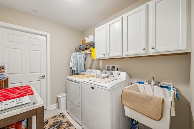 washroom featuring light tile patterned flooring, washing machine and dryer, cabinets, and sink