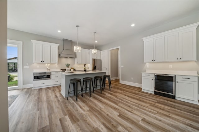 kitchen with light hardwood / wood-style floors, wine cooler, white cabinets, stainless steel fridge with ice dispenser, and custom exhaust hood