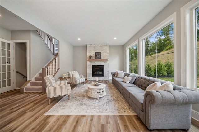 living room featuring brick wall, light hardwood / wood-style flooring, and a brick fireplace