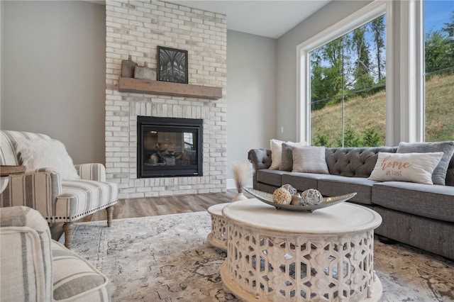 living room with light hardwood / wood-style flooring, brick wall, and a brick fireplace