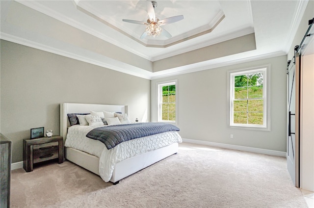 carpeted bedroom with ornamental molding, multiple windows, a tray ceiling, ceiling fan, and a barn door