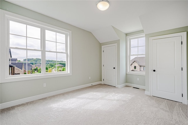 bonus room featuring vaulted ceiling, light carpet, and a healthy amount of sunlight