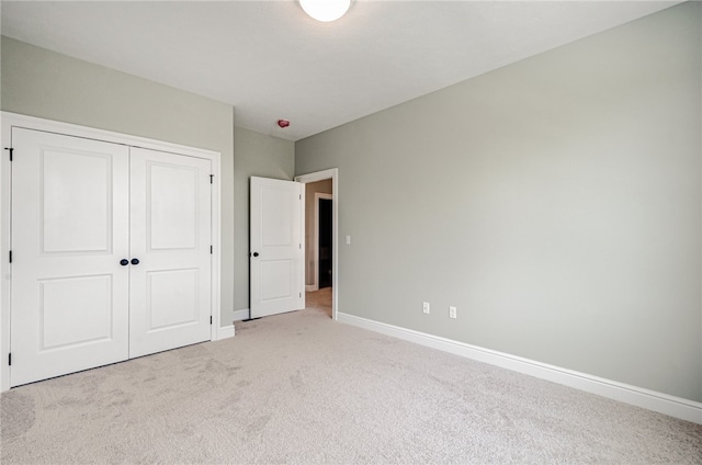 unfurnished bedroom with light carpet and a closet