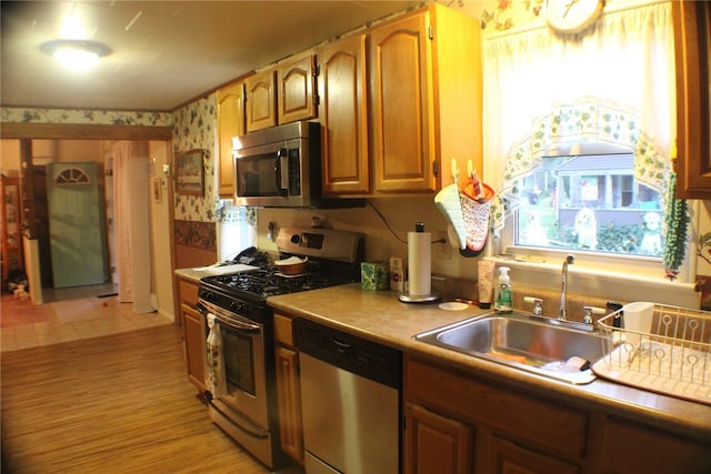 kitchen with sink, stainless steel appliances, and light wood-type flooring