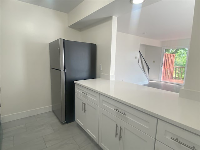 kitchen featuring white cabinets, stainless steel fridge, and light tile patterned floors