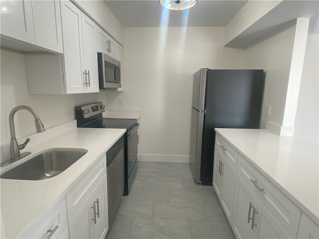 kitchen with light tile patterned floors, appliances with stainless steel finishes, sink, and white cabinets