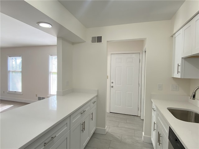 kitchen featuring sink, dishwasher, white cabinets, and light tile patterned floors