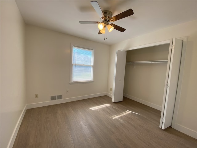 unfurnished bedroom with ceiling fan, a closet, and hardwood / wood-style floors