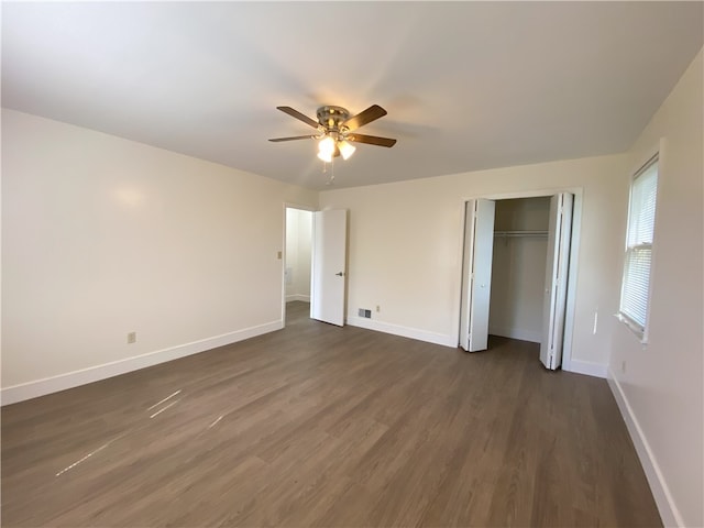 unfurnished bedroom featuring ceiling fan, a closet, and dark wood-type flooring