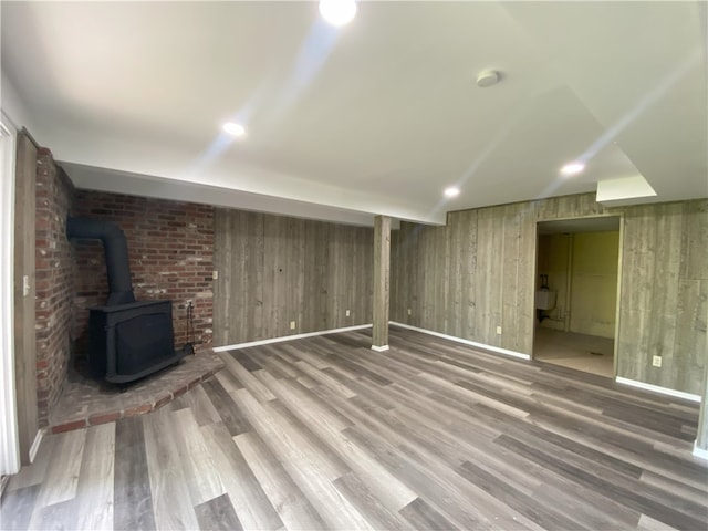 basement with wooden walls, hardwood / wood-style floors, and a wood stove