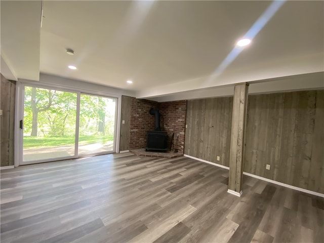 basement featuring wood-type flooring and a wood stove