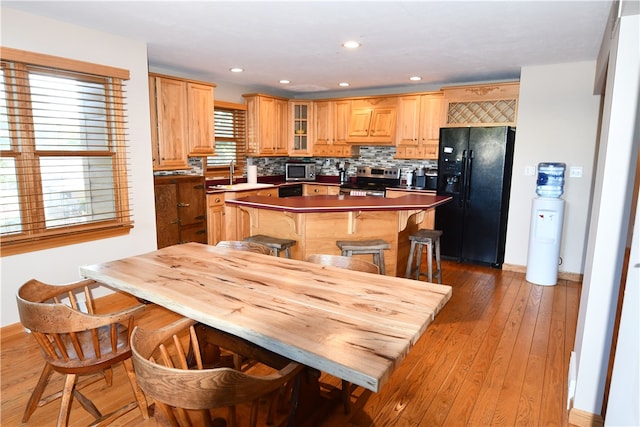 kitchen featuring backsplash, sink, a kitchen bar, light hardwood / wood-style floors, and stainless steel appliances