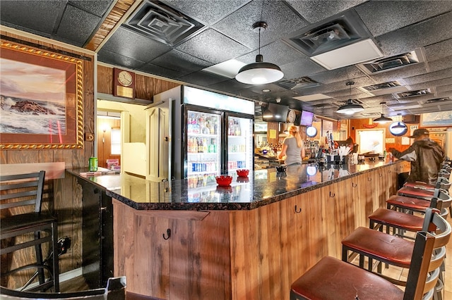 bar featuring a drop ceiling and dark stone countertops