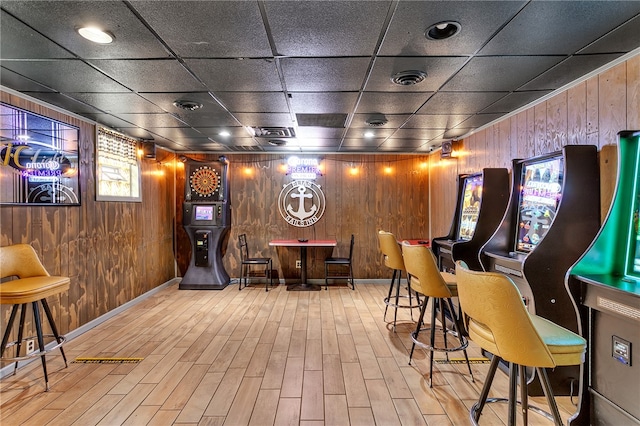 rec room featuring hardwood / wood-style floors, a drop ceiling, bar area, and wood walls