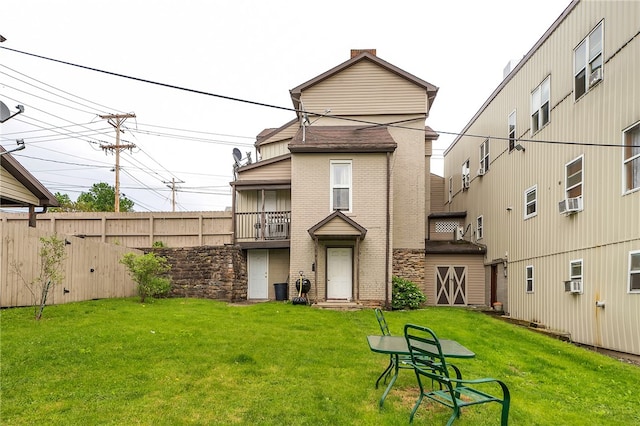 rear view of house featuring a balcony and a lawn