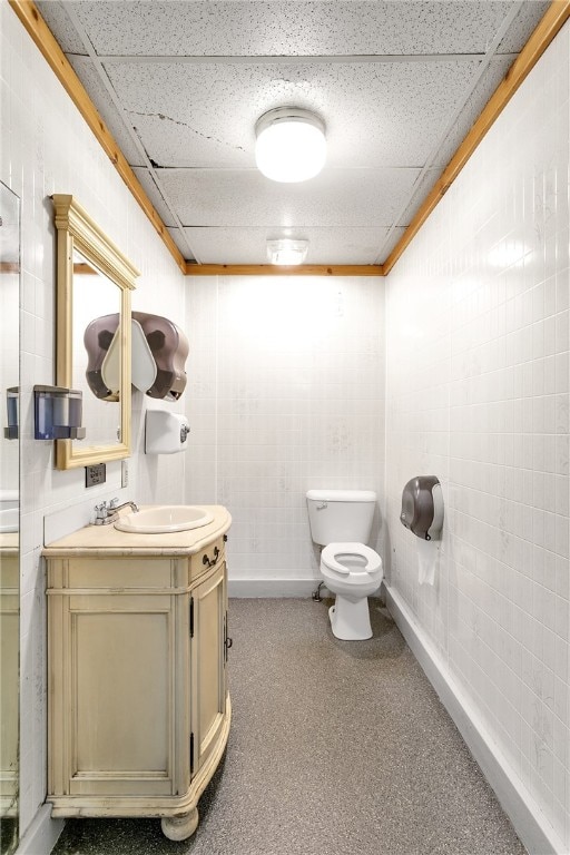 bathroom featuring toilet, vanity, and a drop ceiling