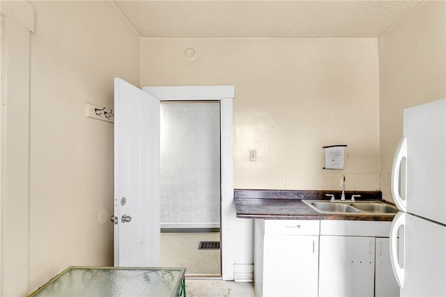 kitchen featuring sink, white refrigerator, and a textured ceiling