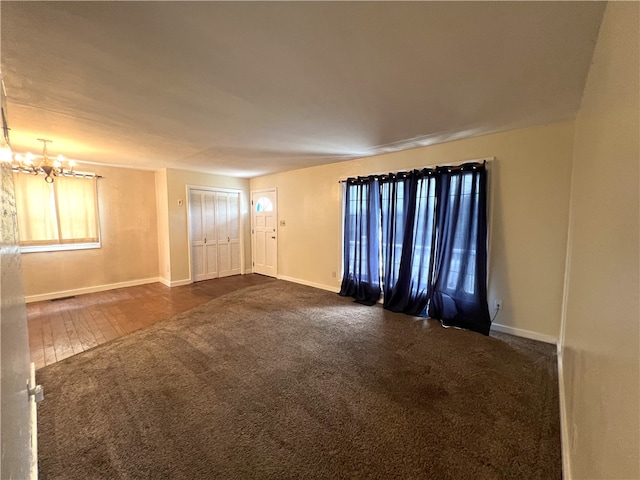 empty room featuring dark carpet and a chandelier