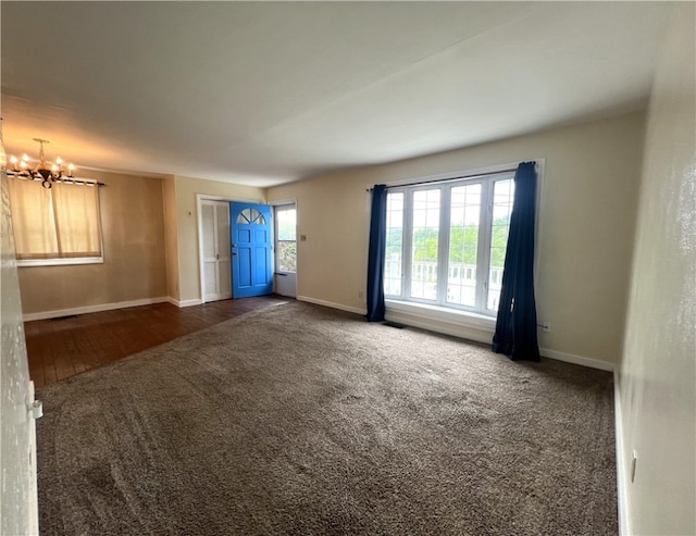 empty room featuring dark colored carpet and a chandelier