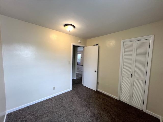 unfurnished bedroom with a closet and dark carpet