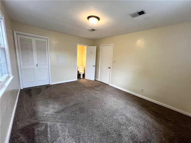 unfurnished bedroom with a closet, carpet, and ensuite bath