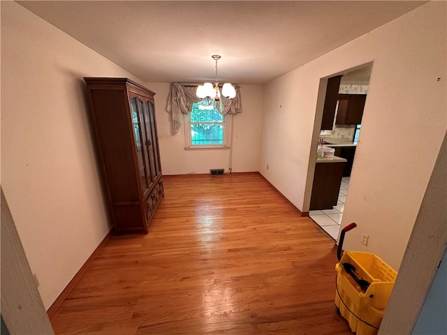 unfurnished dining area featuring light hardwood / wood-style flooring and an inviting chandelier