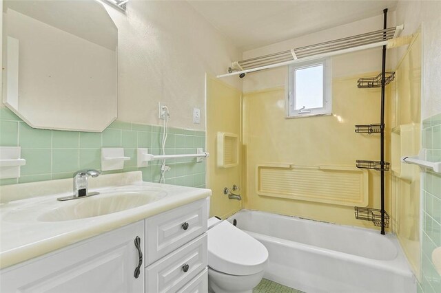 full bathroom with shower / bathing tub combination, toilet, vanity, and tile walls